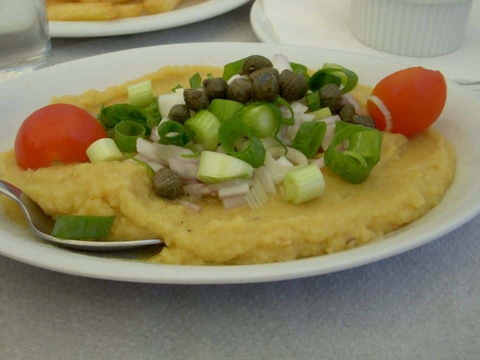 Fava din mazăre galbenă cu ceapă roșie, capere și salată de roșii, gata de servit