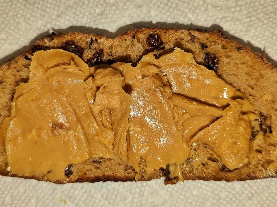 Pâine integrală prăjită cu unt de arahide, banană și semințe de cânepă, gata de servit