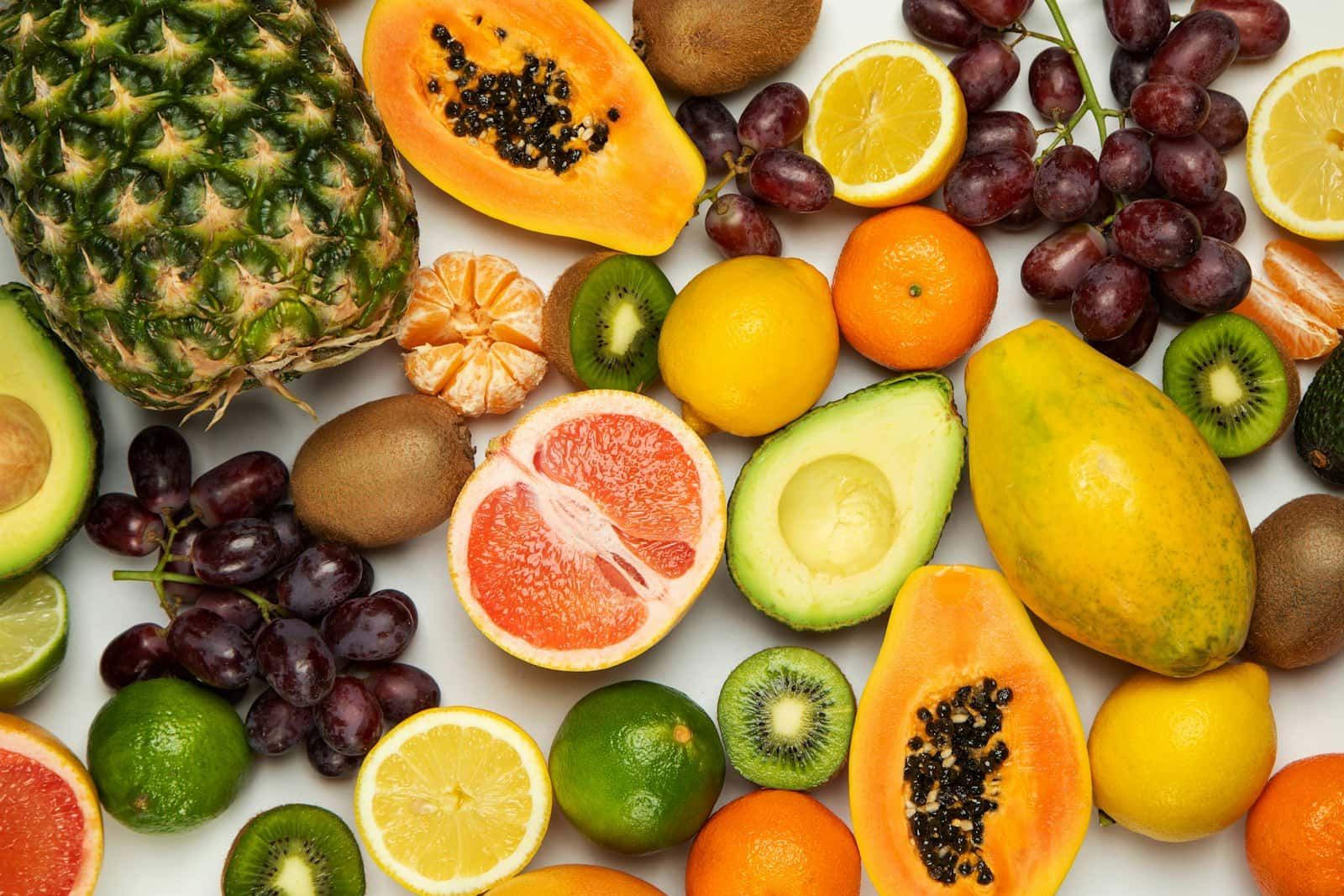 Fructe proaspete tăiate, văzute de sus: papaya, grapefruit, kiwi, avocado și struguri